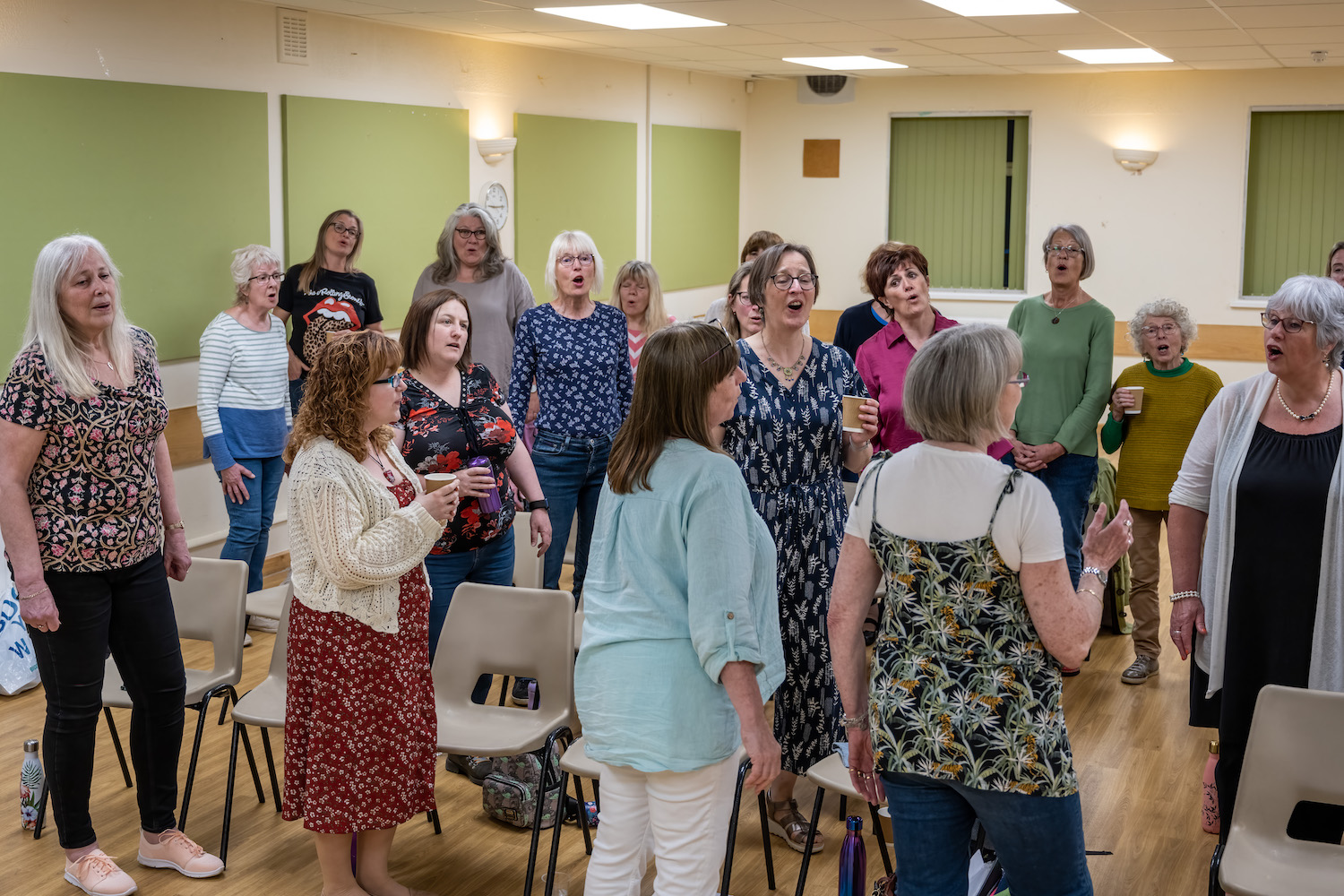 A group of women standing in a semi-circle and singing their hearts out.